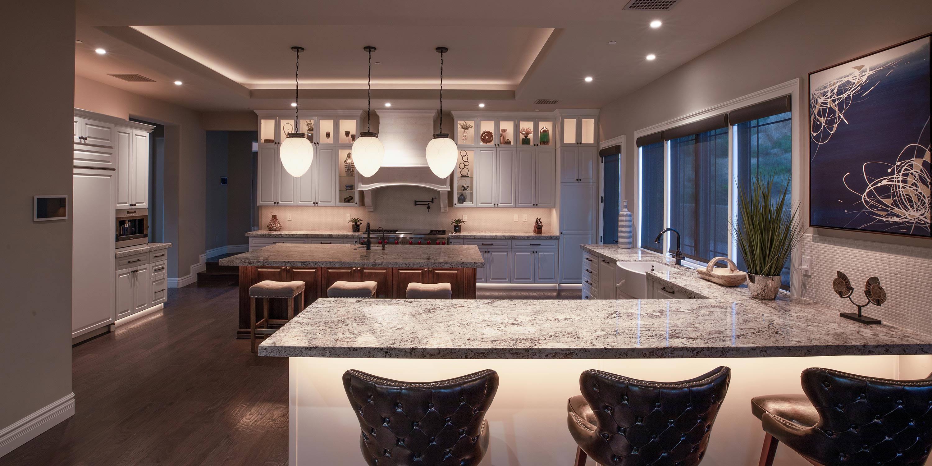 Elegant kitchen with granite countertops, pendant lighting, and bar stools